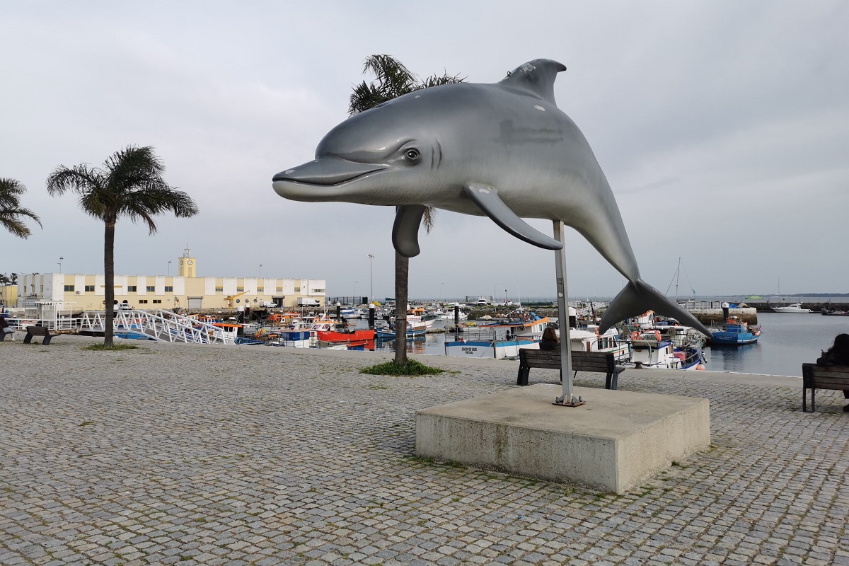 A dolphin sculpture along the port promenade at sunset for Setubal cannabis travel guide CannaTrailz.