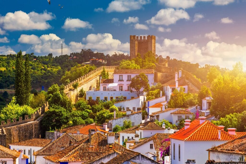 Óbidos village with its castle atop a hill at sunset for cannabis in Óbidos travel guide