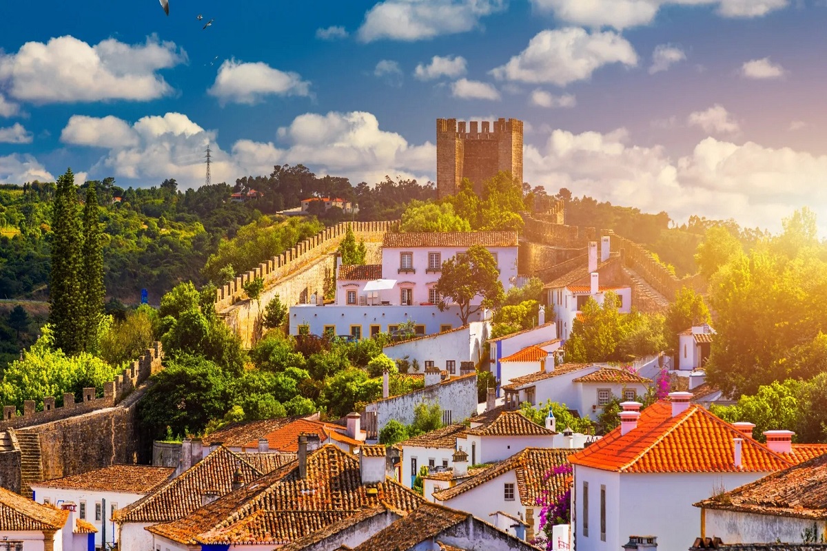 Óbidos village with its castle atop a hill at sunset for cannabis in Óbidos travel guide