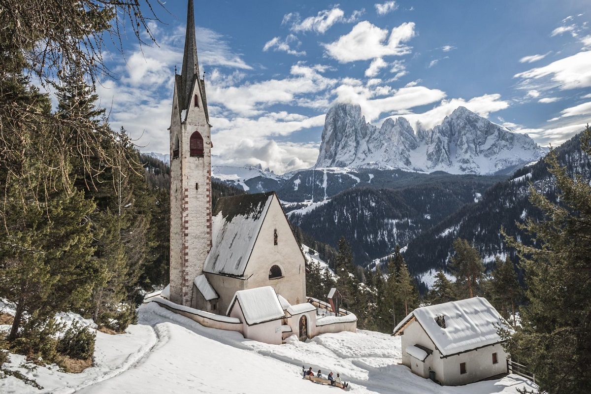 Snow-covered church+mountain for Cannabis in Ortisei Travel Guide.