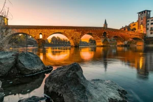 Adige River sunset reflections at Ponte Pietra in Verona, Italy.
