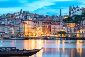 Illuminated cityscape reflects on the Douro River at night in Porto, Portugal.