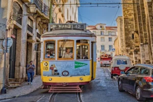 Yellow vintage tram navigating the streets on a sunny day in Lisbon, Portugal.