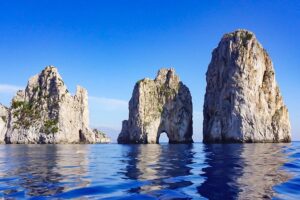 The 3 Faraglioni rock formations on blue waters off the coast of Capri.