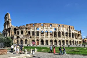 Tourists exploring the iconic Colosseum on a sunny day in Rome, Italy.