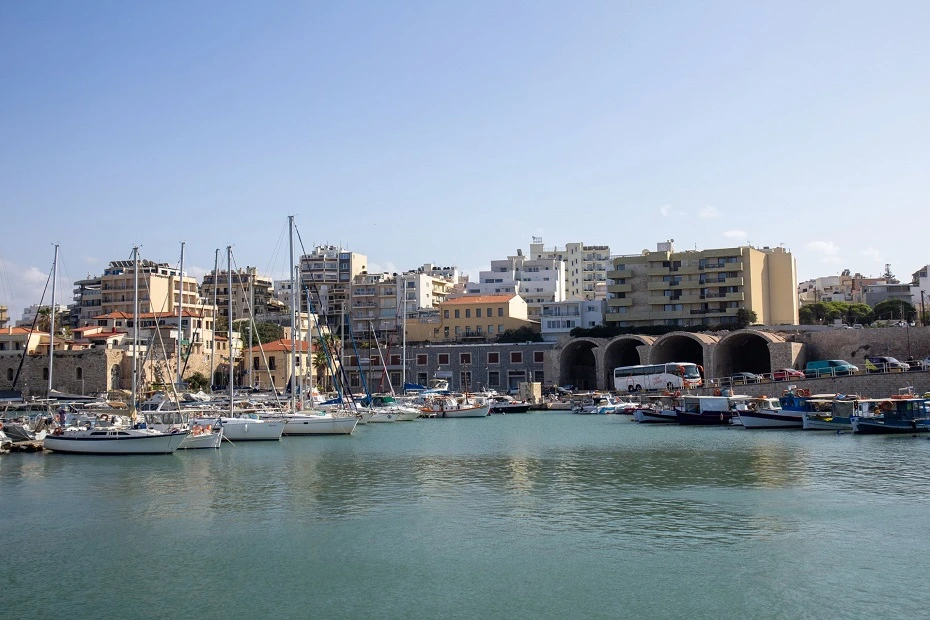 View of the marina with yachts, boats and city buildings on a sunny day in Heraklion, Crete Island, Greece.