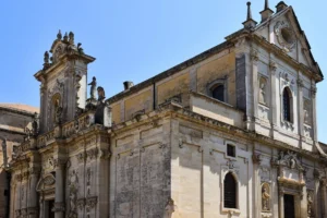 Baroque architecture of the Duomo di Lecce under clear blue skies in Lecce, Italy.