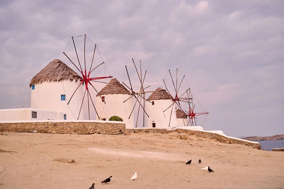 The three iconic whitewashed windmills under ambient sky in Mykonos Island, Greece.
