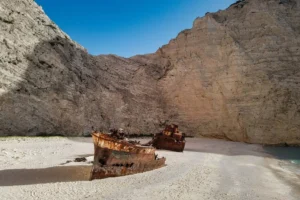 Rusty shipwreck at Navagio beach surrounded by cliffs on a sunny day on Zakynthos Island, Greece.