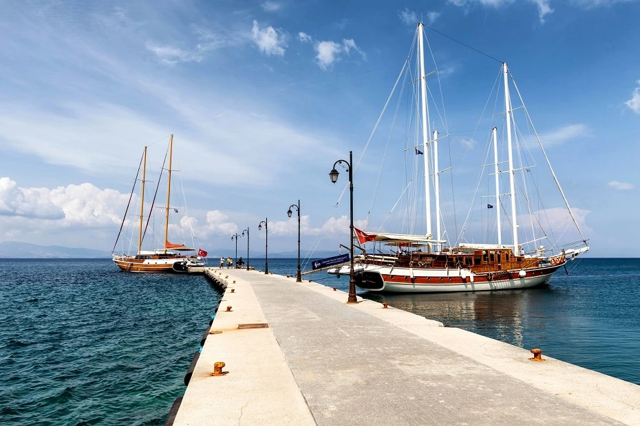 Moored sailboats along a concrete pier on a bright summer day in Kos Island, Greece.